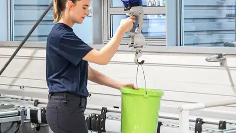 female operator using vacuum lifting equipment to lift a bucket